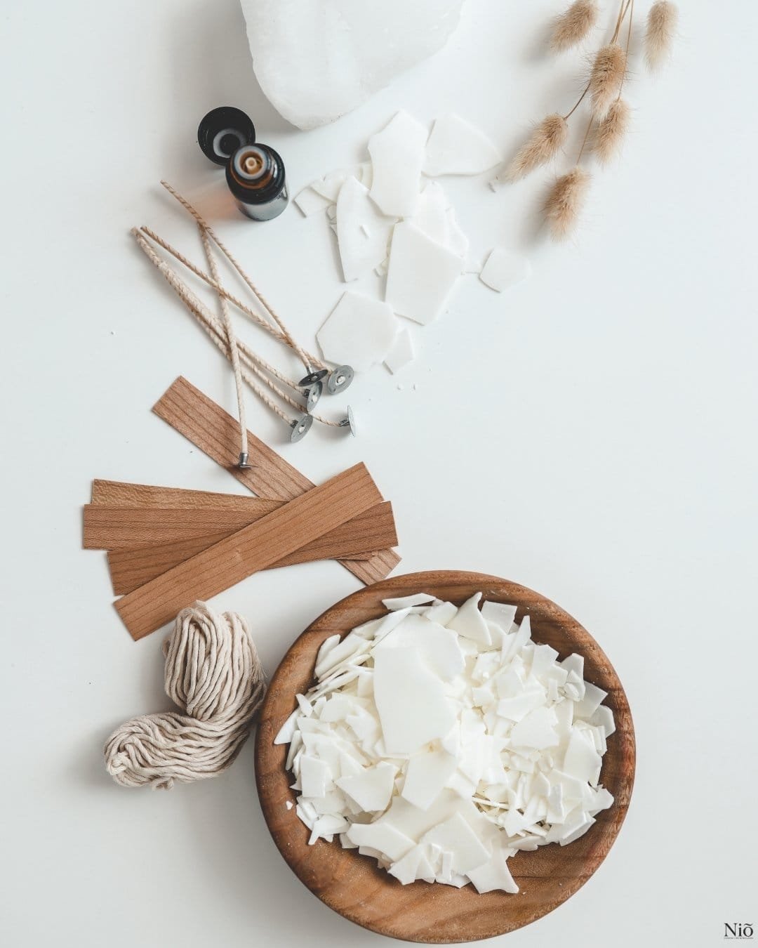 Image représente un récipient avec la cire de soja, les mèches en coton et en bois, un brin de la lavande séchée, une fiole de fragrance, représentant le savoir-faire et matières de Niõ