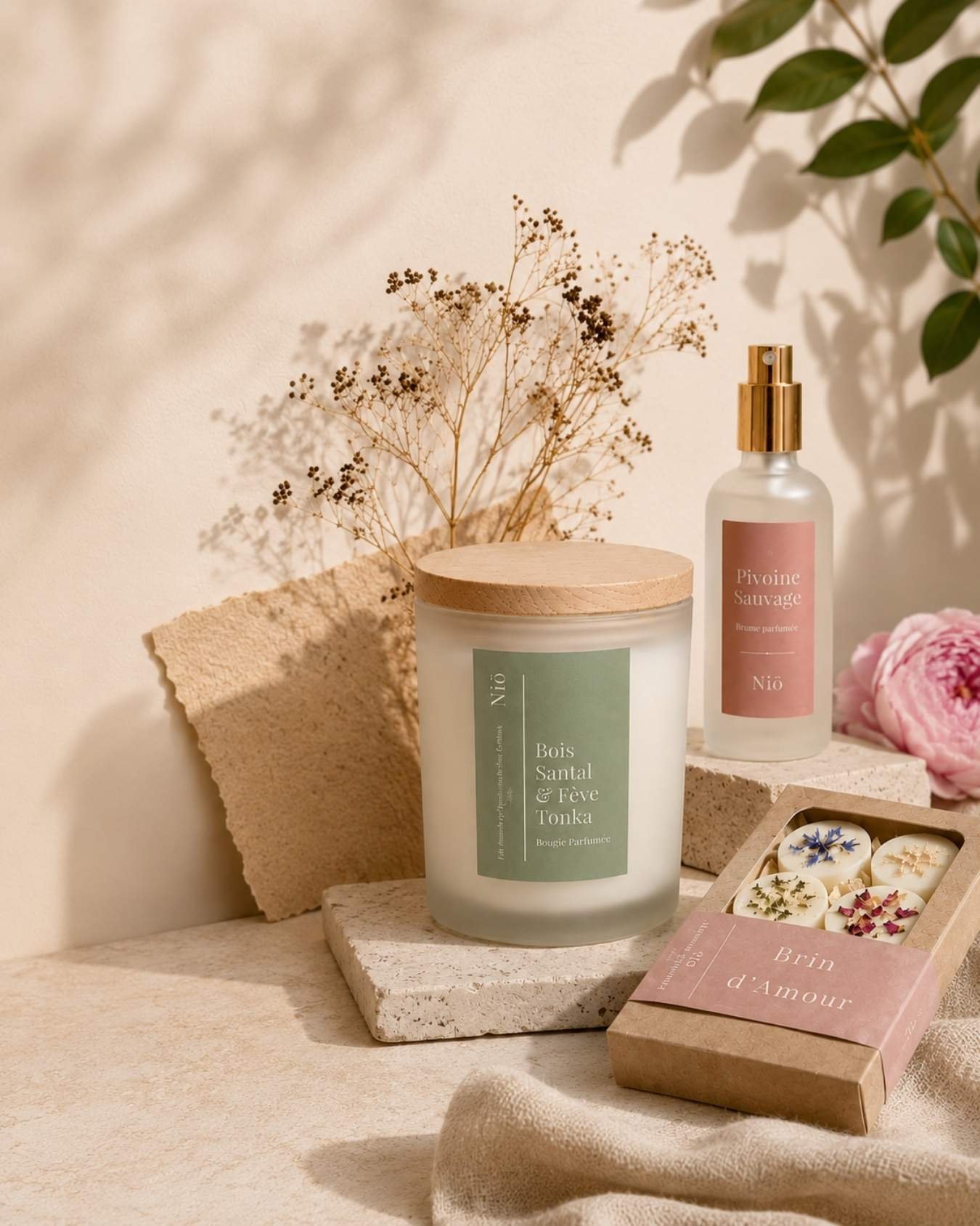 Bougie parfumée, brume d'intérieur et fondants parfumés Niõ dans une ambiance naturelle et artisanale aux tons doux.