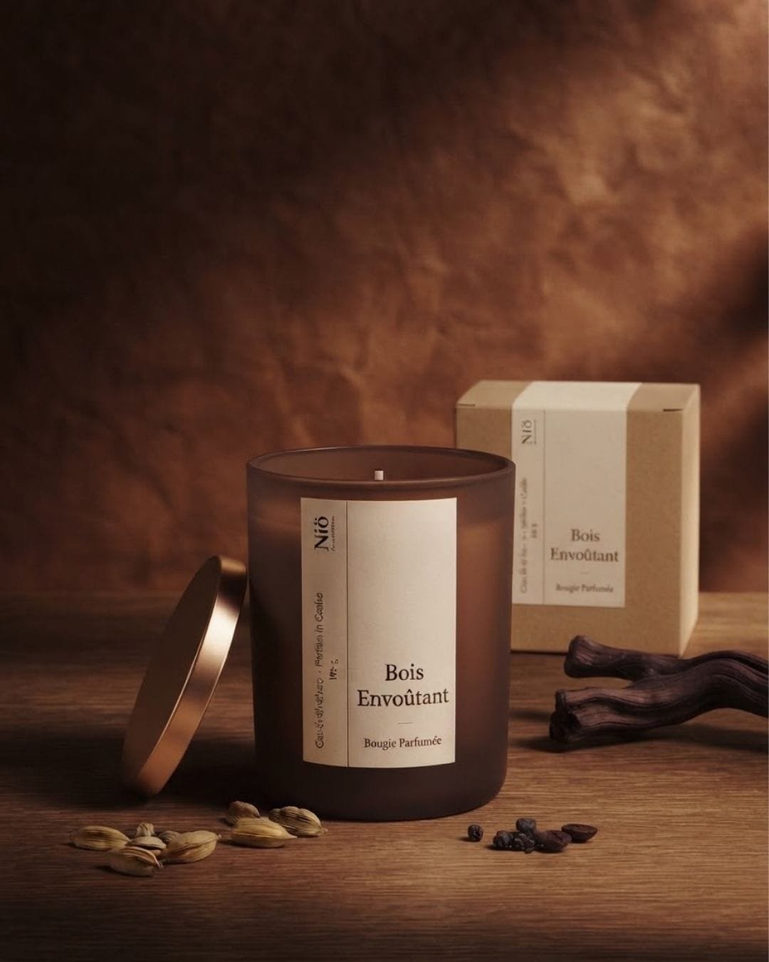 Bougie Bois Envoûtant et son écrin kraft dans une lumière chaude, sur un fond de bois sombre.
