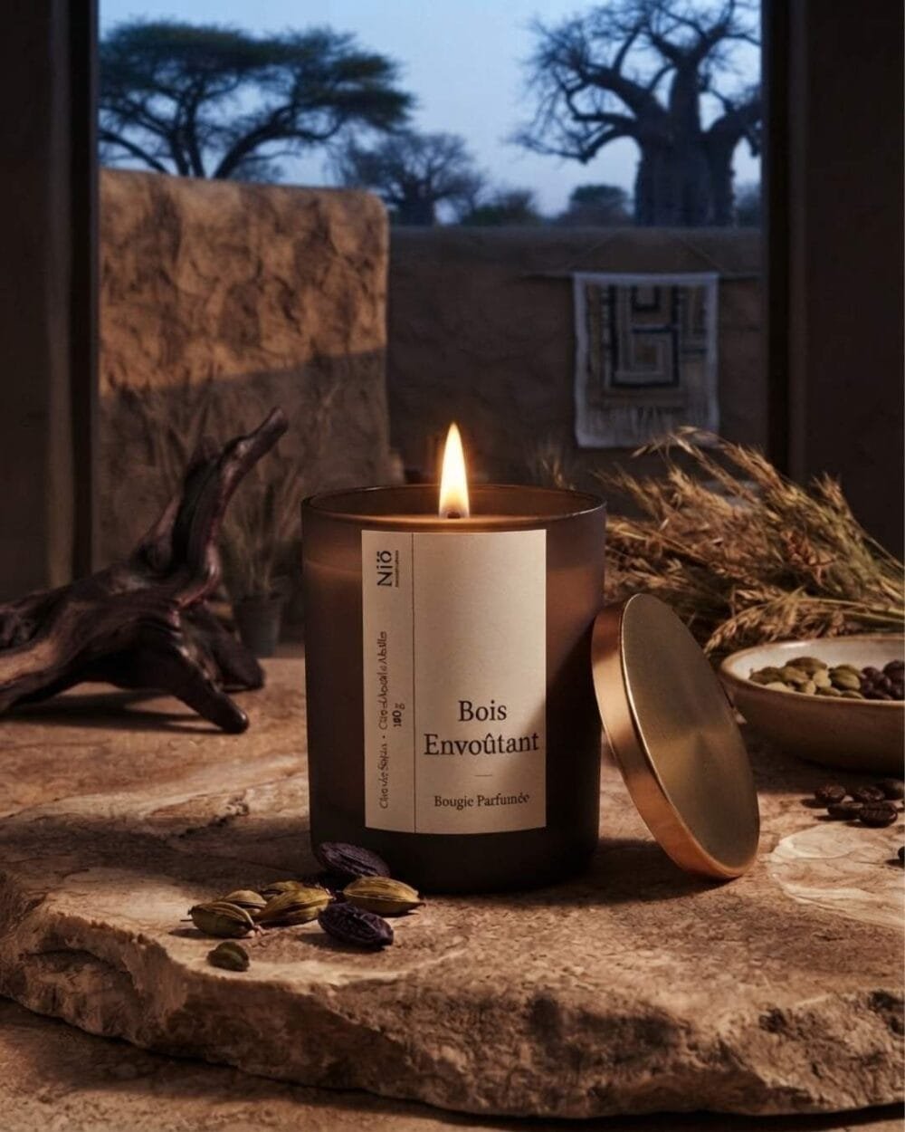 Bougie parfumée Bois Envoutant de Niõ allumée au bord d'une fenêtre