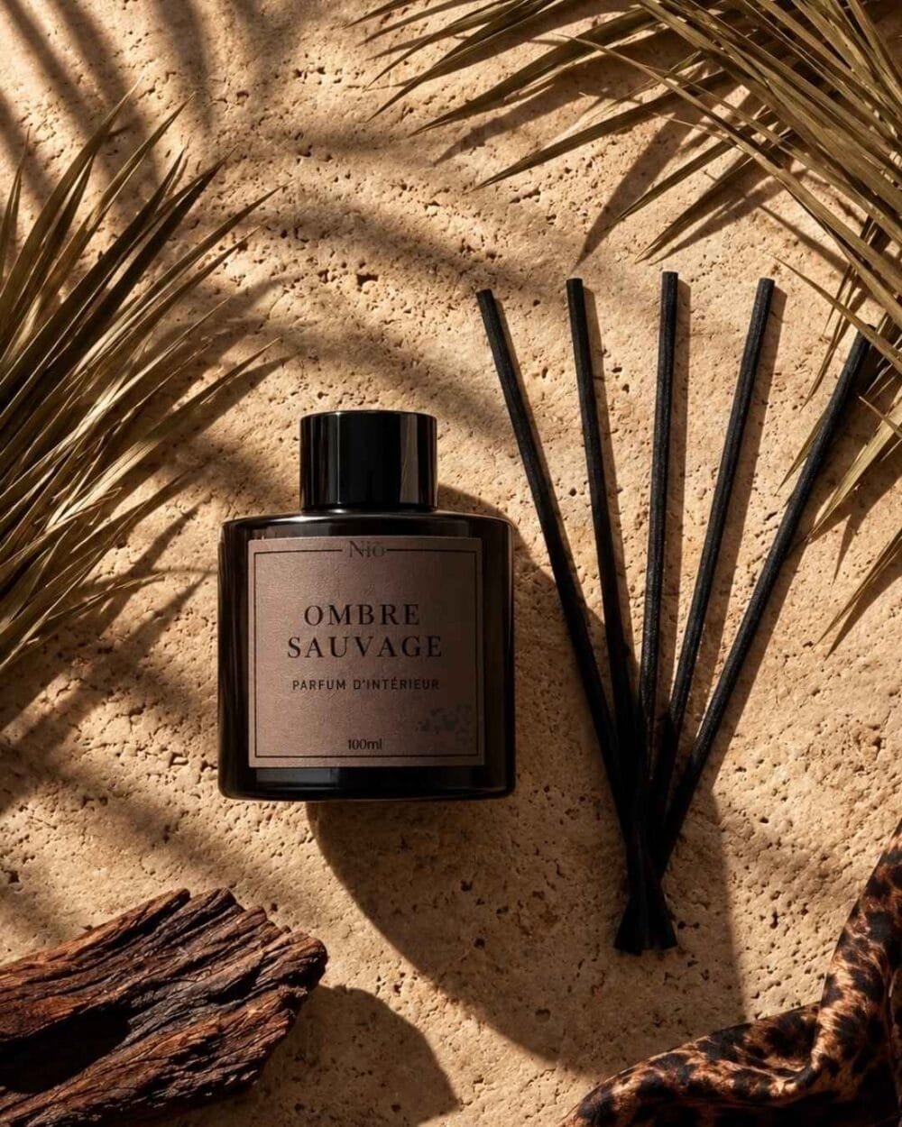 Diffuseur à bâtonnets Ombre Sauvage au cœur d'une scène hivernale : pierre, écorces et botaniques séchés.