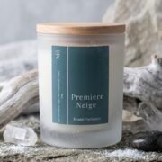 Bougie parfumée Première Neige de la Collection Nuit Polaire, hiver 2026/2027, signée Niõ, dans une ambiance hivernale, sur un socle en pierre naturelle, entourée de givre et de neige