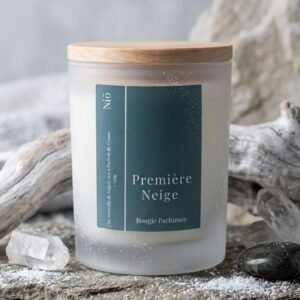 Bougie parfumée Première Neige de la Collection Nuit Polaire, hiver 2026/2027, signée Niõ, dans une ambiance hivernale, sur un socle en pierre naturelle, entourée de givre et de neige