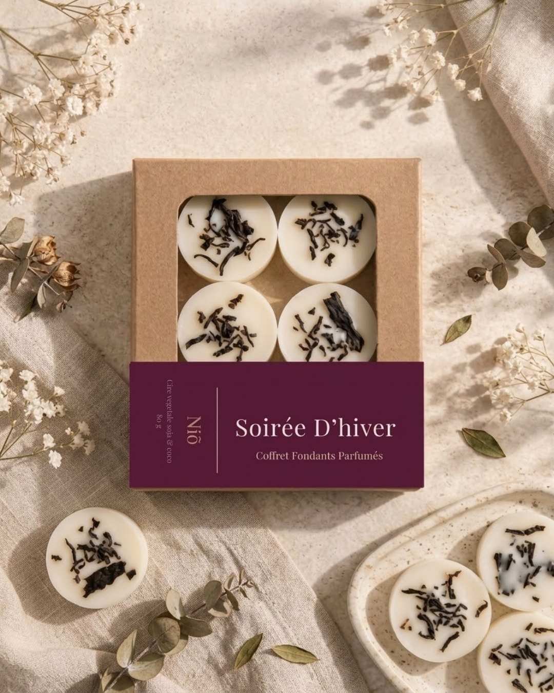 Belle composition de fondants parfumés Soirée d'Hiver de Niõ dans leur écrin avec l'étiquette, avec des épices hivernales et de Noel autour comme décor